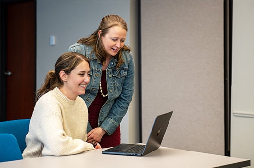 lori kendall helping woman on laptop in meeting