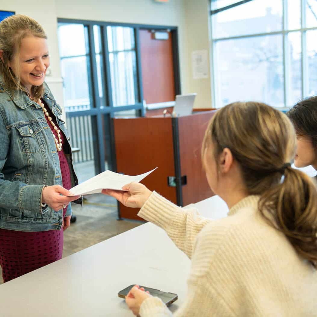 a student taking a paper from lori kendall