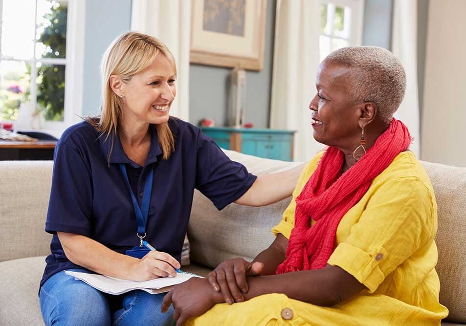 female support worker visits with woman on couch