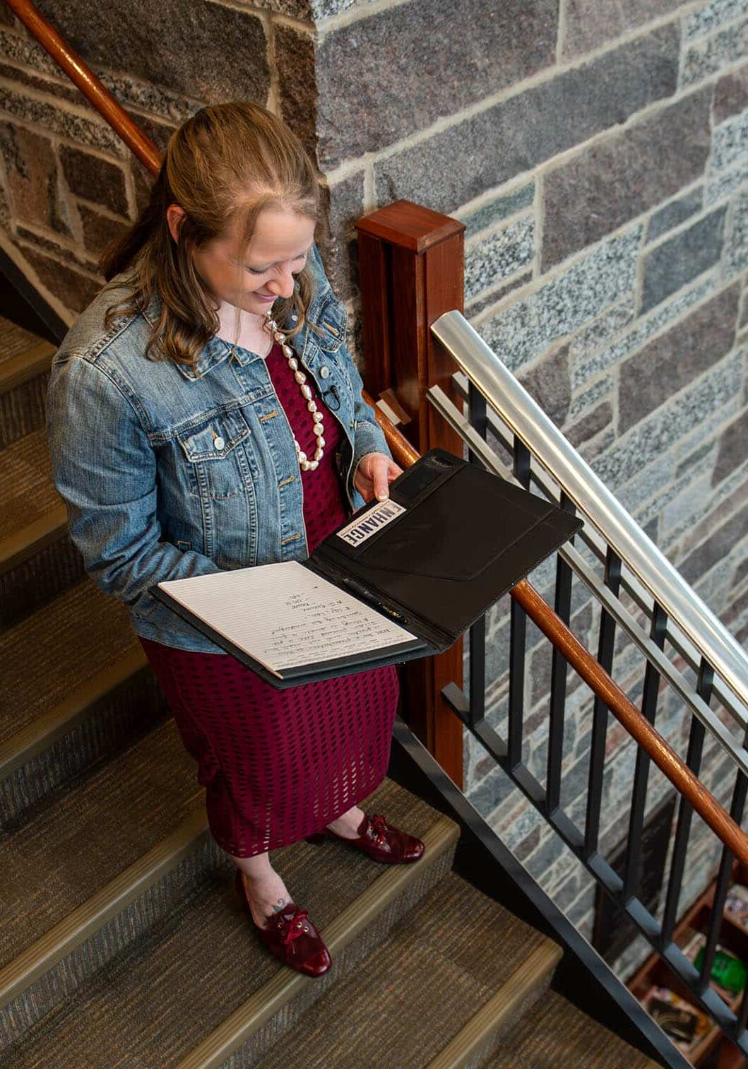 lori kendall standing on the stairs and looking at a book